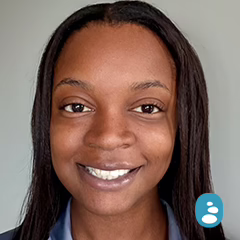 A woman with straight, dark hair smiles at the camera against a plain background. An icon of a person is in the bottom right corner of the image. - OYESPA Aveda Lifestyle | nver Grove Heights, MN